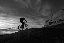 Mountain Biker Climbing The Slickrock Waves Of The Slickrock Trail As The Sunsets , Moab , Utah