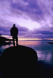 Silhouette Of A Man Standing On A Rock Looking Out To Sea