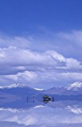 Travellers Disembark From Their Luxury 4x4 Vehicle Onto The Salar De Uyuni Recent Snows Have Left A Water Skimmed , Highly Reflective Surface Spectacular Scenery And The Expansive Salt Flats Stretch To The Horizon Incredible Reflection S Of The Sky In The Water Snow Capped Peaks Beyond Bolivia , South America