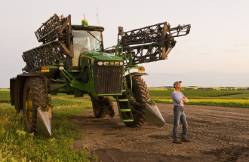 A Man Looks Out From A High Clearance Sprayer In Early Evening Light , Near Somerset , Manitoba , Canada