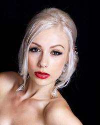 Portrait Of Pretty Young Woman With Blond Hair Up Against A Black Background