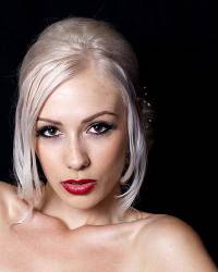 Portrait Of Pretty Young Woman With Blond Hair Up Against A Black Background