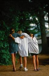 Three Girls Walk With Their Arms Across Each Other’s Shoulders At Summer Camp In Vermont , United States , North America .