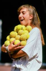 A Teenage Girl Wearing Teeth Braces Carries A Large Group Of Yellow Tennis Balls At Summer Camp In Vermont , United States , North America .