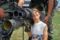 A Five Year Old Boy Makes A Funny Face As He Peeks Through The Sighting Mechanism Of A Bazooka At A Display Put On By The National Guard In Plainfield , New Hampshire , United States .