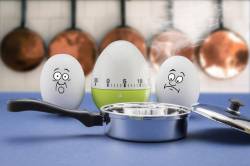 Two Eggs With Frightened Face Look At A Frying Pan In A Kitchen
