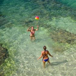 Two Young Women Are  Playing With A Ball In The Clear Water Of The Adriatic Sea