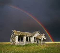 A Long Abandoned, Depression Era Farm House On The Wyoming Plains Underneath A Stormy Summer Sky And Rainbow