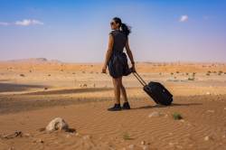 Lady In The Desert With Her Luggage Looking At The Dunes In The Desert Of The United Arab Emirates (UAE)