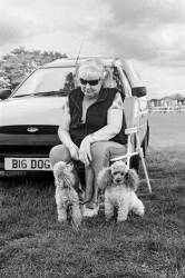 Two Poodles And Their Owner, Sitting In Front Of Their Van At The Dog Show