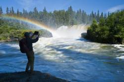 Hiker Taking A Photo At  Pisew Falls Along The Grass River, Manitoba, Canada