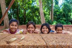 Four Cambodian Children Peek Over A Wall Begging For Money At Banteay Srei, Cambodia.