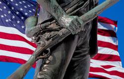 Minute Man Bronze Statue With American Flag At Concord And Lexington, Massachusetts, USA.