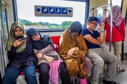 Four Young People On A Long, Early Morning Commute On A Monorail In Kuala Lumpur, Malaysia.