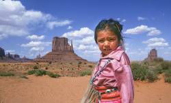 A Young Navajo Girl, Dressed In Traditional Velveteen Clothing And Silver And Turquoise Jewelry, Near Her Mother’s Hogan In Monument Valley Navajo Tribal Park, Arizona/Utah.
