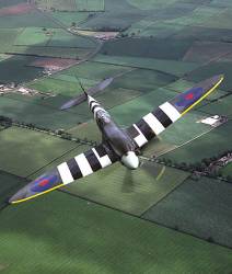 Supermarine Spitfire MkXIX ( Bearing Invasion Stripes ) In Flight Over Land