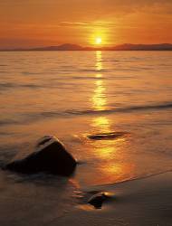 Llanfair , Gwynedd , Wales / June Sunset Across Tremadog Bay From The Beach With Wet Rocks And Sand In The Foreground And The Lleyn Peninsula Beyond