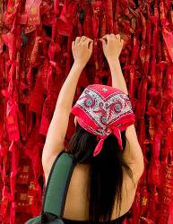 Young Asian Female Tying A Lucky Charm In A Buddhist Temple