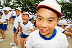 A Japanese Elementary School Student Poses Mischieviously While His Friends Look On And Laugh