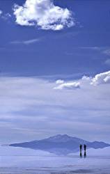 A Pair Of Travellers Alone On The Salt Flats Of The Salar De Uyuni After Recent Snows Have Left A Water Skimmed , Highly Reflective Surface Spectacular Scenery And The Expansive Salt Flats Stretch To The Horizon Reflections Of The Sky And Figures In The Water Bolivia , South America