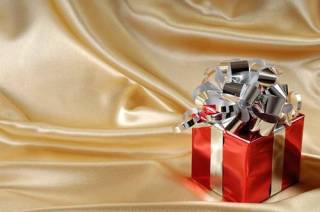  Stock photo of a Red fancy Christmas gift box with a silver bow on golden background with copy space on the left 